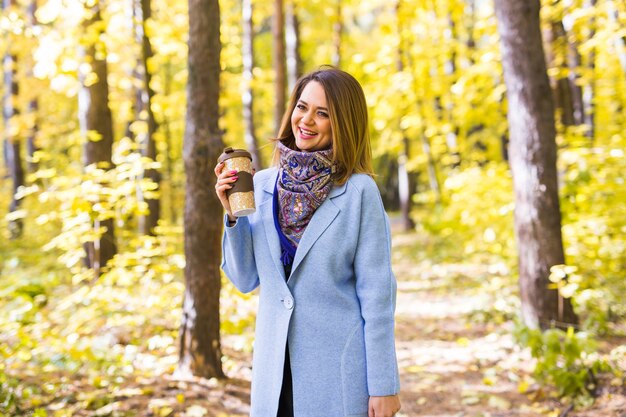 Jovem mulher bonita com casaco azul segurando uma xícara de café