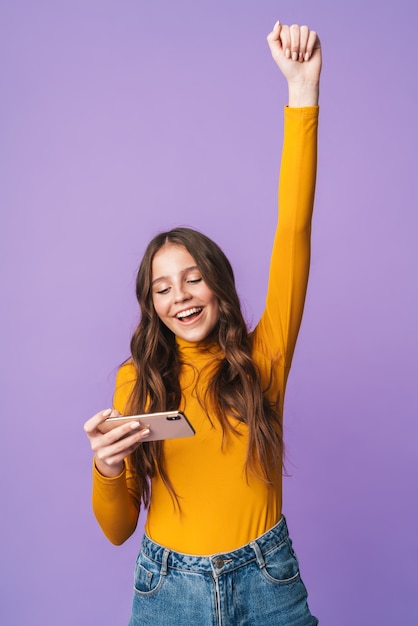 jovem mulher bonita com longos cabelos castanhos alegrando-se e segurando o celular isolado