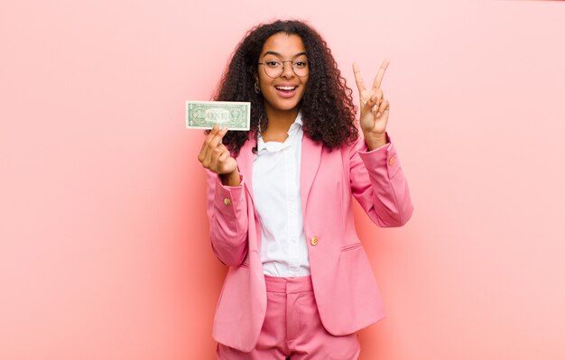 Jovem mulher bonita com notas de dólar contra parede rosa