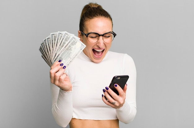 Jovem mulher bonita com notas de dólar e um smartphone