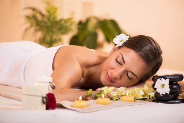 Jovem mulher bonita com os olhos fechados relaxando e desfrutando no centro de spa.