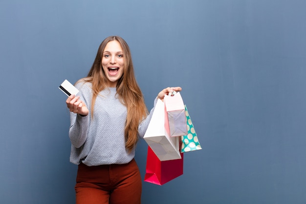 Jovem mulher bonita com sacos de compras contra o azul com uma copyspace