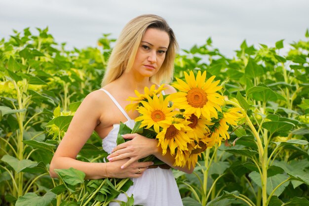 Jovem mulher bonita com um buquê de girassóis em um campo de girassóis