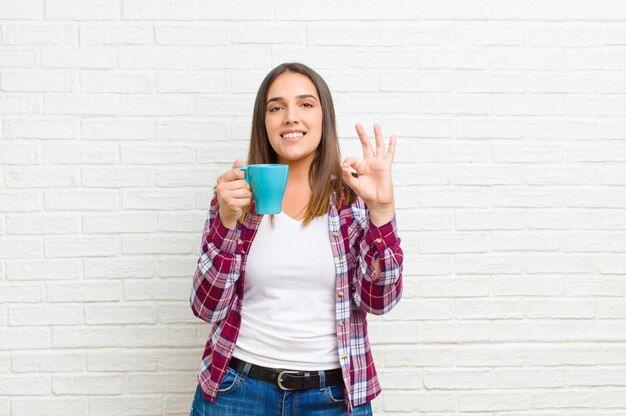 Jovem mulher bonita com um café na textura da parede de tijolo