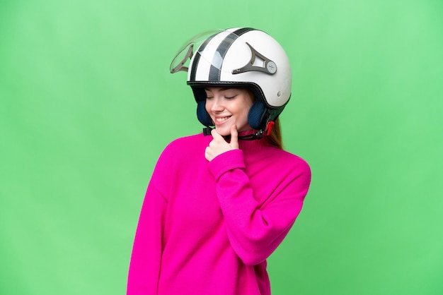 Jovem mulher bonita com um capacete de moto sobre fundo croma chave isolado, olhando para o lado e sorrindo