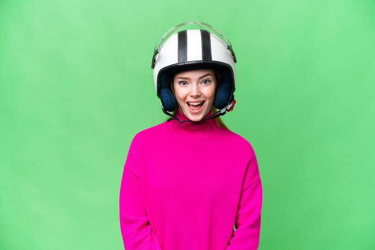 Foto jovem mulher bonita com um capacete de motocicleta sobre fundo croma isolado com expressão facial de surpresa