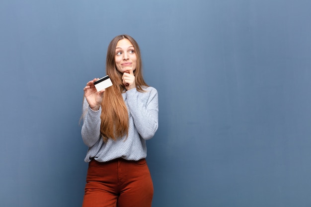 Jovem mulher bonita com um cartão de crédito contra o azul com uma copyspace