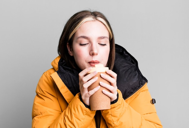 Jovem mulher bonita com um casaco e um café para viagem