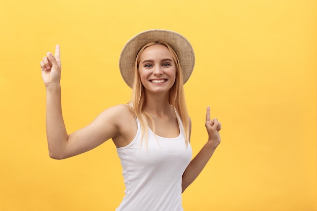 Jovem mulher bonita dançando no estúdio isolado em fundo amarelo