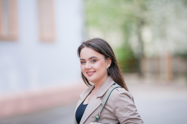 Jovem mulher bonita de 19 anos em roupas elegantes Modelo com cabelos escuros em roupas casuais caminha pela cidade florescente da primavera Quente