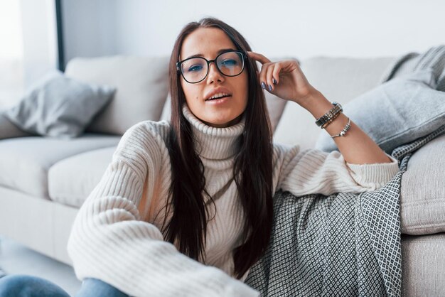 Jovem mulher bonita de óculos sentado em casa sozinho.