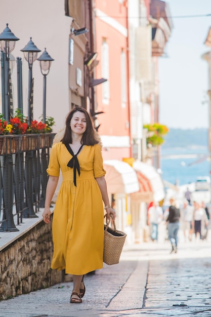 Jovem mulher bonita de vestido amarelo andando pelas ruas da pequena cidade de porec ao fundo