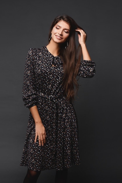 Foto jovem mulher bonita de vestido curto posando sobre fundo cinza escuro