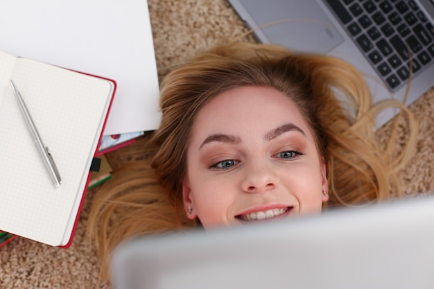 Jovem mulher bonita deitar no chão tem muito trabalho segurar tablet nos braços