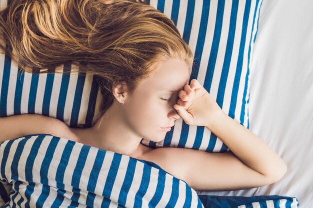 Jovem mulher bonita dormindo em sua cama e relaxante pela manhã.