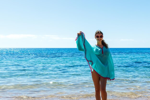 Jovem mulher bonita e feliz na praia dançando brincando correndo e se divertindo nas férias de verão