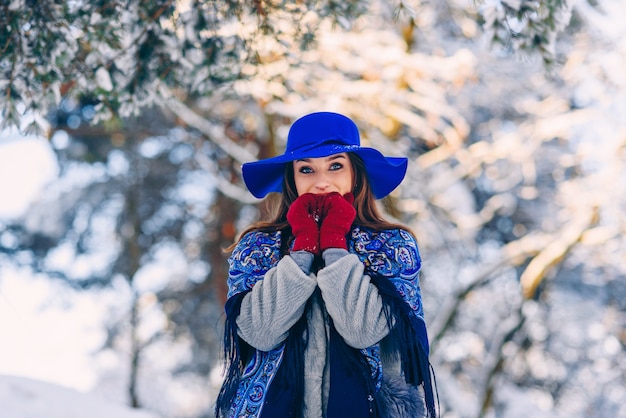 Jovem mulher bonita elegante de chapéu azul e lenço andando no parque