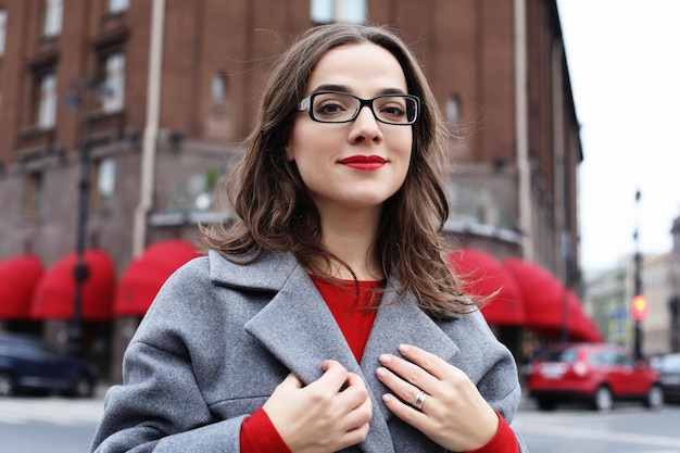 Jovem mulher bonita elegante vestindo casaco cinza vestido vermelho