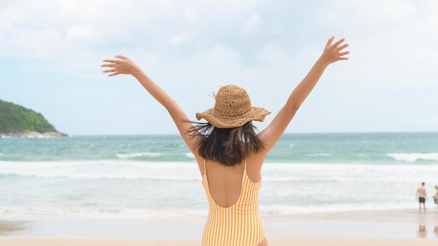 Jovem mulher bonita em biquíni curtindo e relaxando na praia