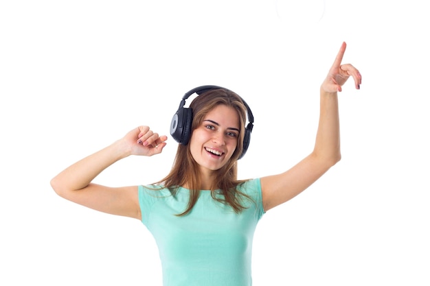 Jovem mulher bonita em camiseta azul ouvindo música em fones de ouvido pretos no estúdio