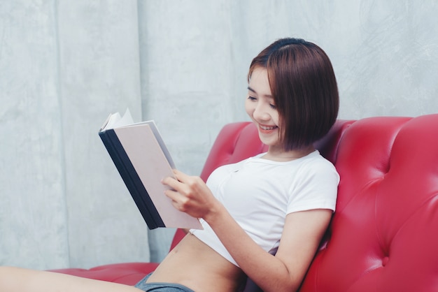 Jovem mulher bonita em lingerie branca lendo livro no descanso da cama