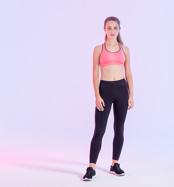 Jovem mulher bonita em pleno crescimento em roupas fitness permanente rosa