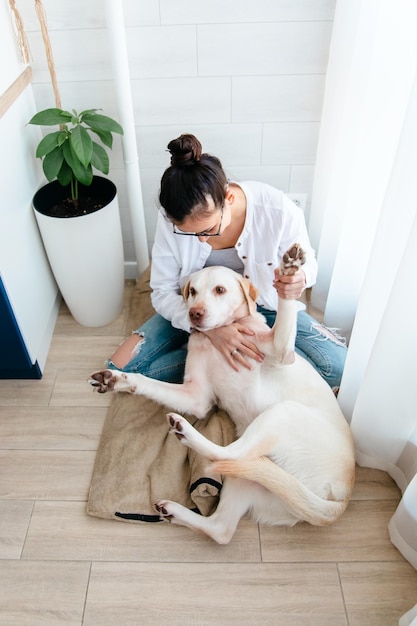 Foto jovem mulher bonita em roupas casuais abraça seu amado cachorro grande enquanto está sentado no sofá na vida