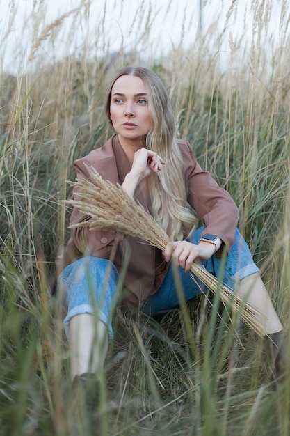 Jovem mulher bonita em um campo ao pôr do sol. andar ao ar livre. feminilidade.