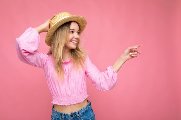 Jovem mulher bonita em uma elegante blusa rosa de verão e um chapéu de palha na moda.