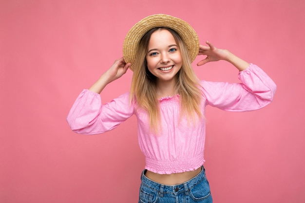 Jovem mulher bonita em uma elegante blusa rosa de verão e um chapéu de palha na moda.