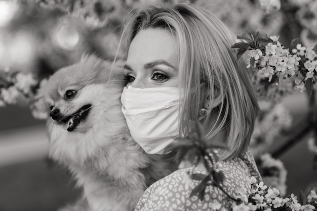 Jovem mulher bonita em uma máscara médica com um cachorro