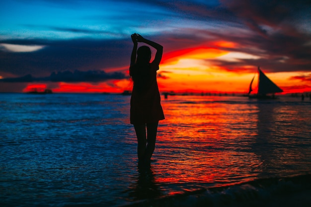 Jovem mulher bonita em uma praia tropical de areia branca ao pôr do sol