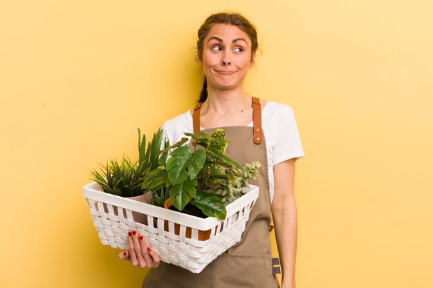 Jovem mulher bonita encolhendo os ombros sentindo o conceito de plantas confusas e incertas