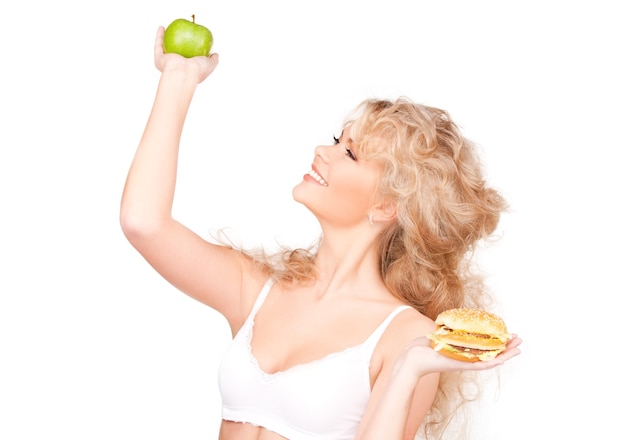 jovem mulher bonita escolhendo entre hambúrguer e maçã