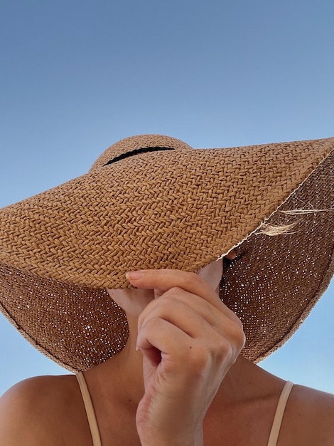 Jovem mulher bonita esconder o rosto com chapéu de palha férias de verão conceito de férias conceito de moda minimalista