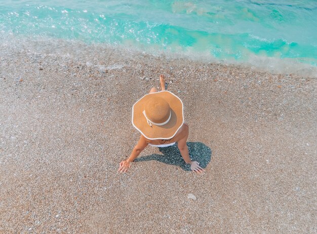 Jovem mulher bonita está sentada no custo do mar e apreciando a paisagem de ondas.