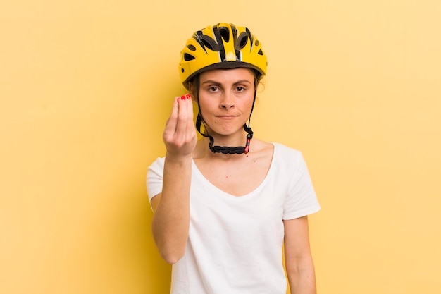 Jovem mulher bonita fazendo gesto de capice ou dinheiro dizendo para você pagar o conceito de bicicleta