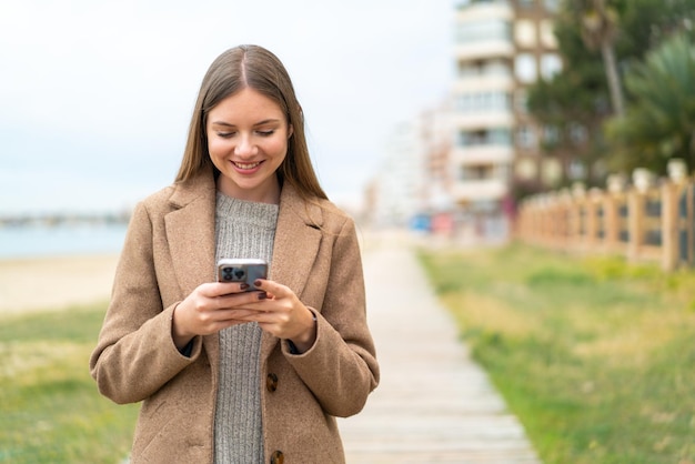 Jovem mulher bonita loira enviando uma mensagem ou e-mail com o celular