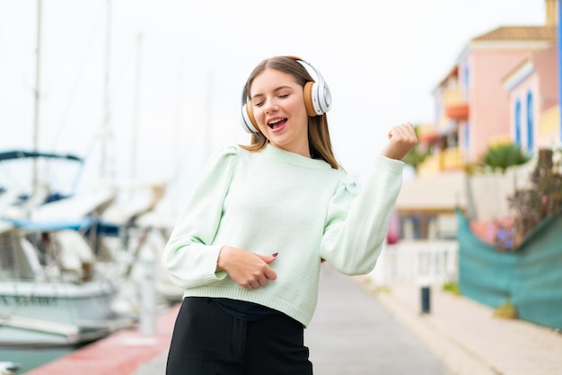 Jovem mulher bonita loira ouvindo música e fazendo gesto de guitarra