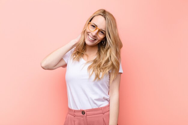 Foto jovem mulher bonita loira rindo alegre e confiante com um sorriso casual, feliz e amigável contra a parede de cor lisa