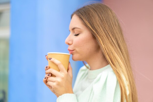 Jovem mulher bonita loira segurando um café para viagem