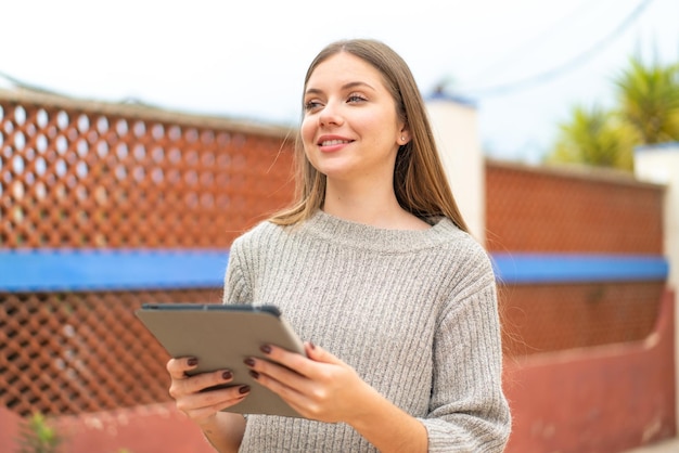 Jovem mulher bonita loira segurando um tablet com expressão feliz