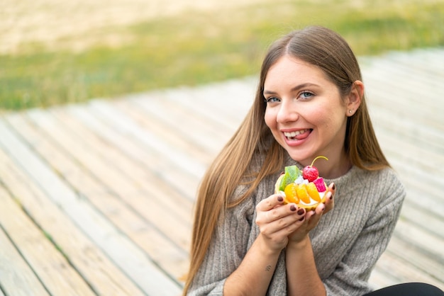 Foto jovem mulher bonita loira segurando uma tortinha com expressão feliz