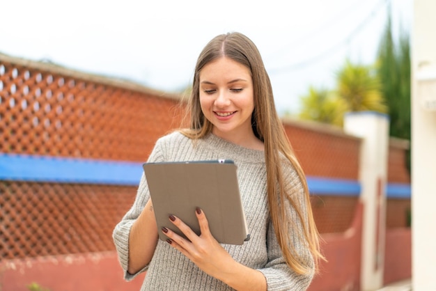 Jovem mulher bonita loira tocando a tela do tablet com expressão feliz