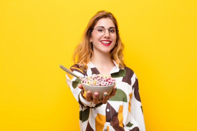 Jovem mulher bonita loira tomando uma tigela de café da manhã