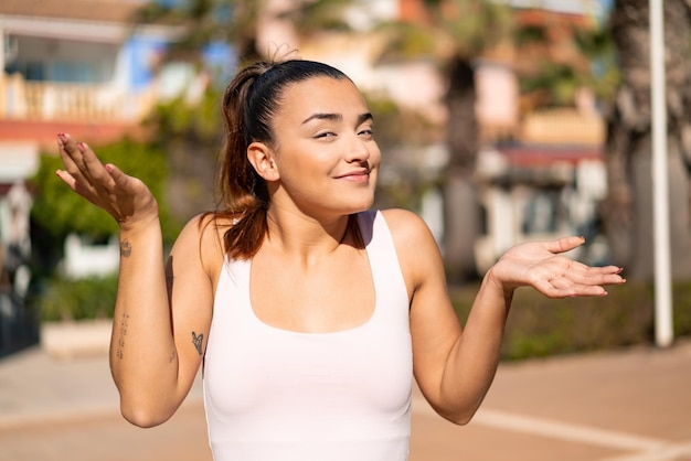 Jovem mulher bonita morena fazendo gesto de dúvidas