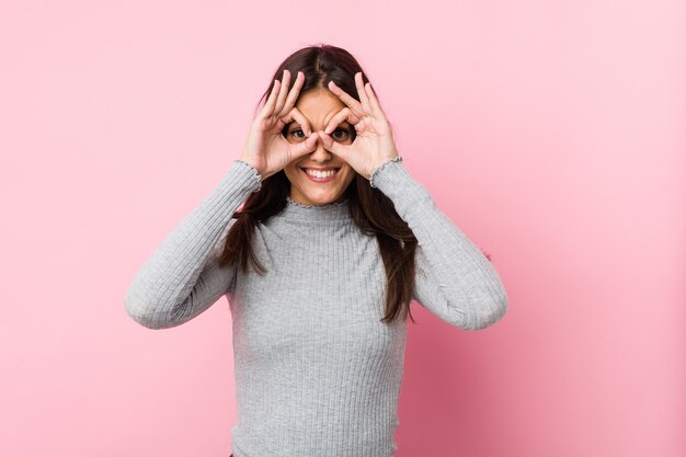 Jovem mulher bonita mostrando sinal bem sobre os olhos