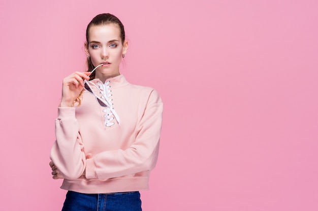 Jovem mulher bonita na camisola rosa e óculos de sol isolados