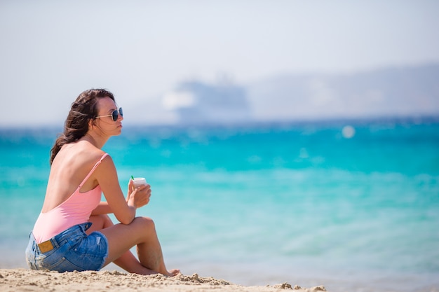 Jovem mulher bonita na praia na Europa. Menina com café de férias em Mykonos, Grécia