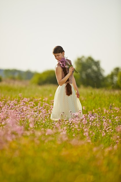 Jovem mulher bonita no campo com flores